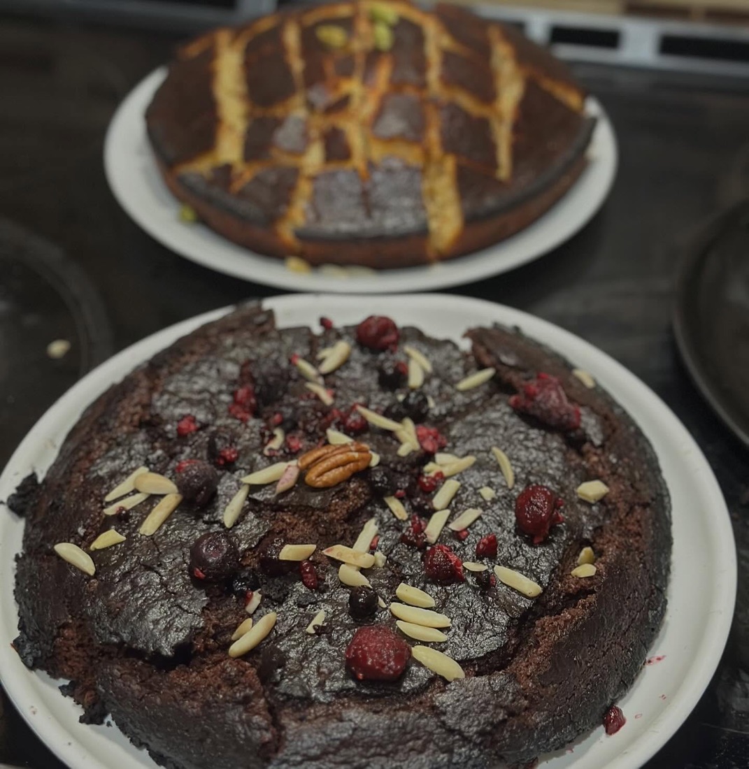 Two homemade chocolate cakes topped with nuts and berries