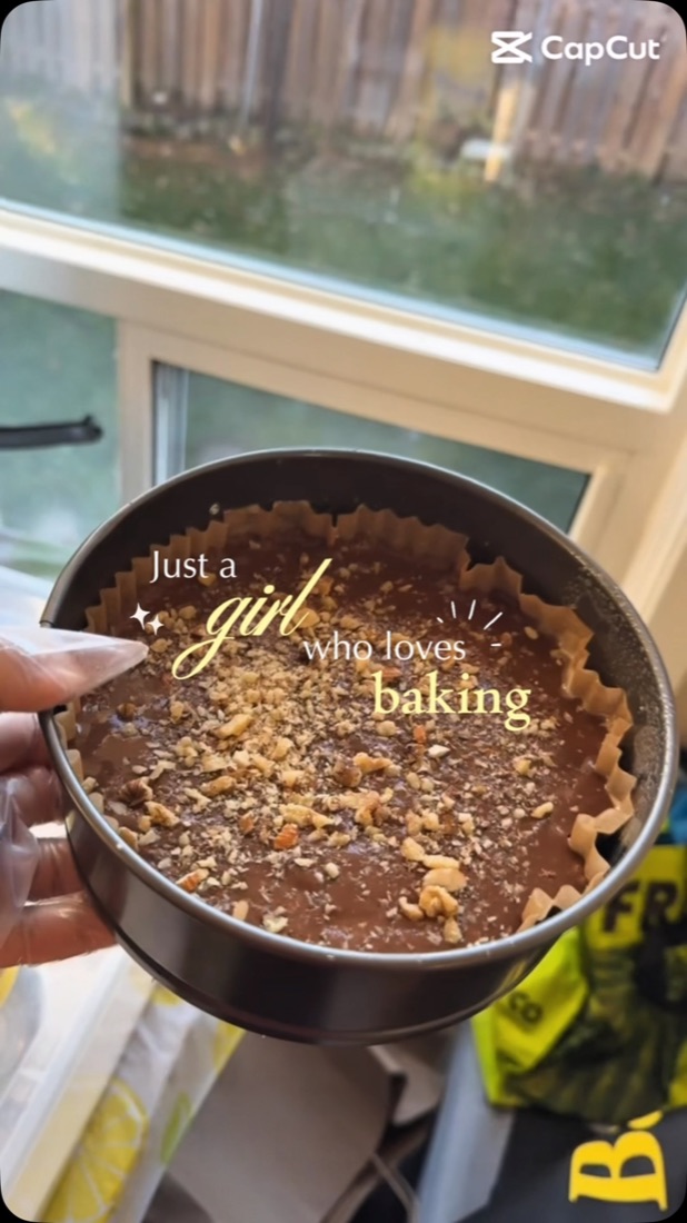 Cake batter topped with walnuts in a baking tin by the kitchen window